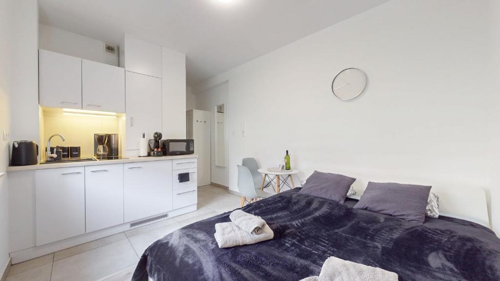 a white bedroom with a bed and a kitchen at Studio Fibra Choco in Rybnik