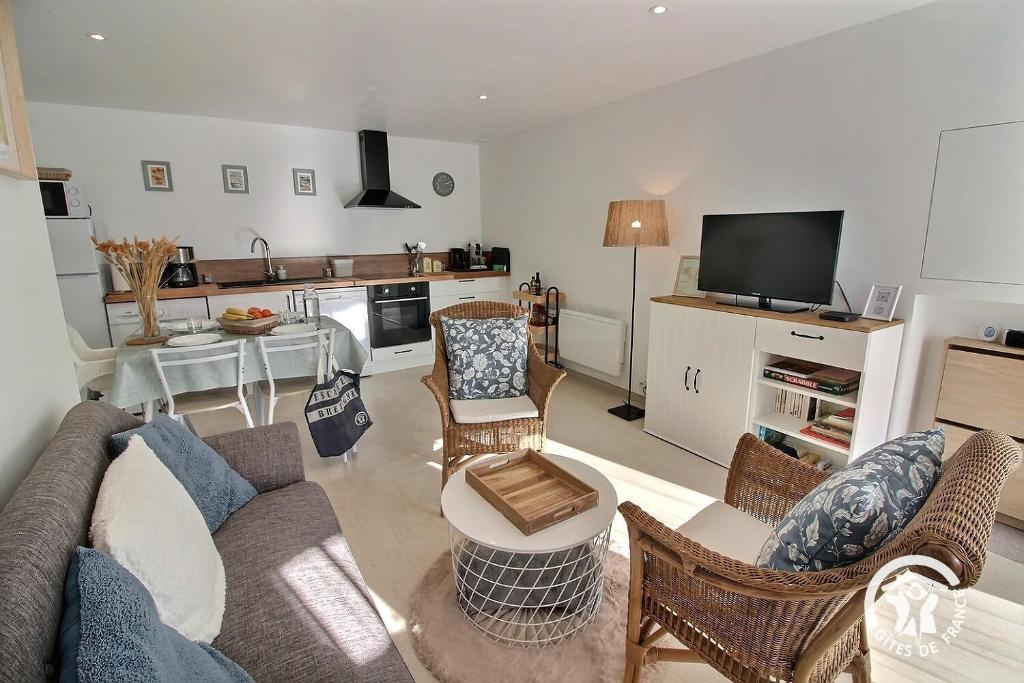 a living room with a couch and chairs and a kitchen at Les pierres d'armor in Vildé-Guingalan