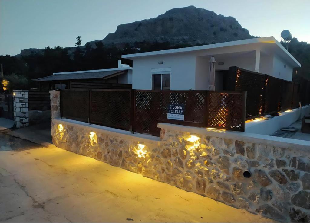 a house with lights on a stone wall at Stegna Holiday in Archangelos