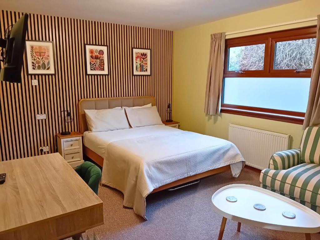 a bedroom with a bed and a table and a chair at Deveron Lodge B&B in Turriff