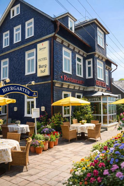 a blue building with tables and chairs in front of it at Burghof Hotel in Schwarzatal