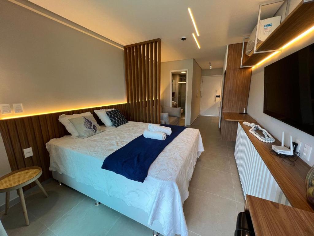 a bedroom with a large bed and a television at Flats Beach Class Verano - Muro Alto, Porto de Galinhas in Ipojuca