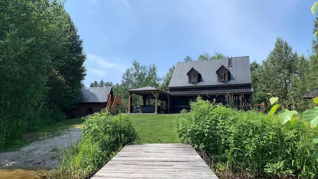 a house with a wooden walkway in front of it at Spa & Kenogami Lake - Chalet le Rustik in Saguenay