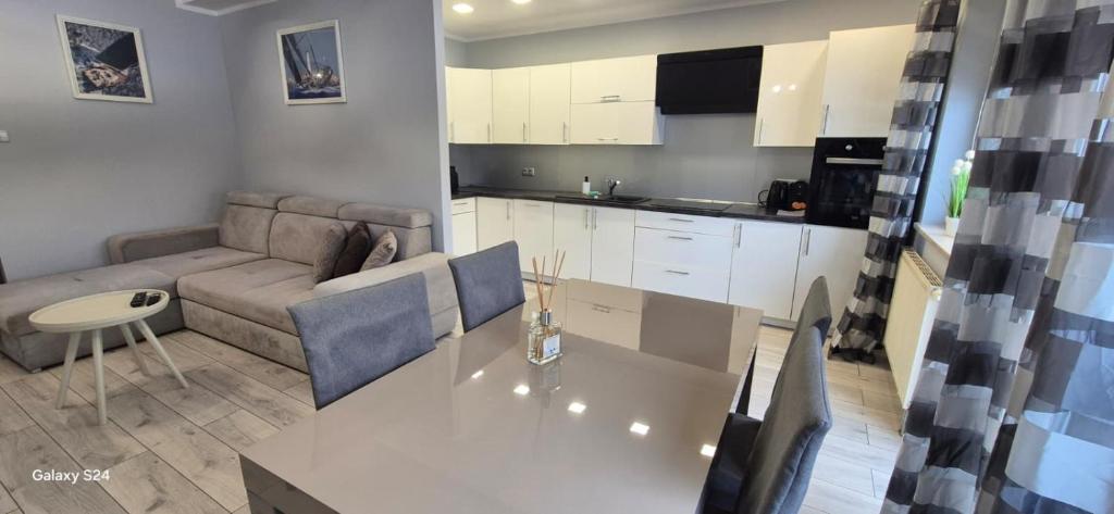 a kitchen and living room with a table and a couch at Apartament SORENTO 7 in Gorzów Wielkopolski