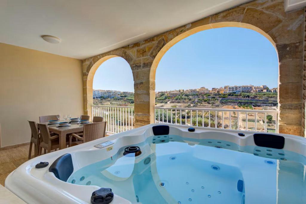 a jacuzzi tub in a room with a balcony at Gozo Getaway! Heated Jacuzzi & Views in Xagħra