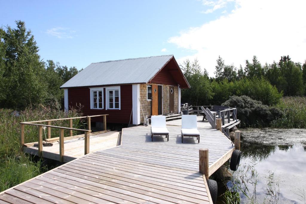 a small cabin with two chairs on a wooden dock at Fisherman's cottage in Björköby