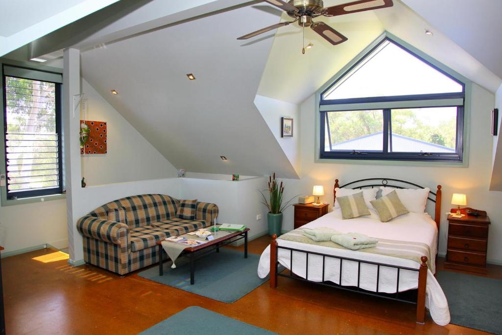 a bedroom with a bed and a couch and a window at Salamander Bay Bed and Breakfast in Salamander Bay