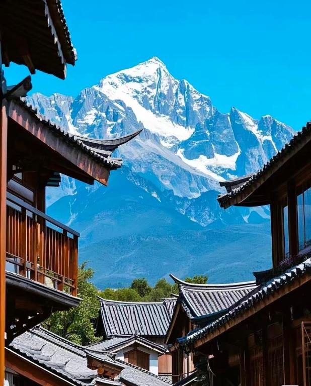 a view of a snow covered mountain from the roofs of buildings at 静山轩 in Lijiang
