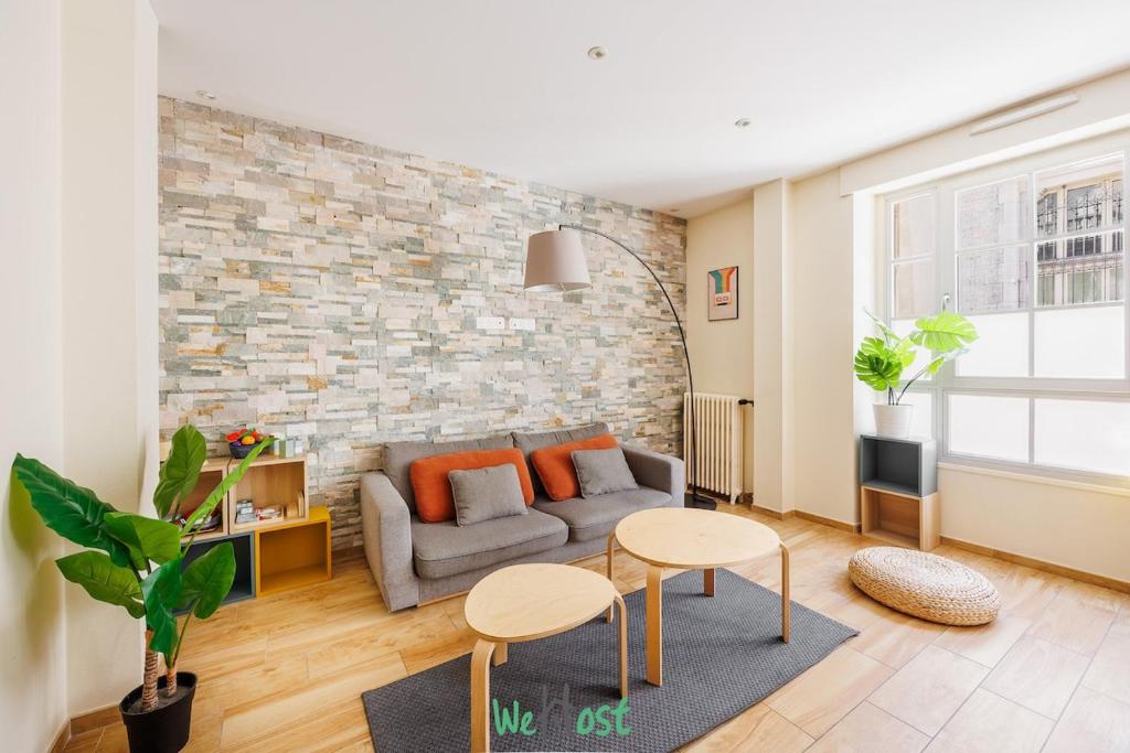 a living room with a couch and a brick wall at Grand T5 lumineux au cœur de Besançon in Besançon