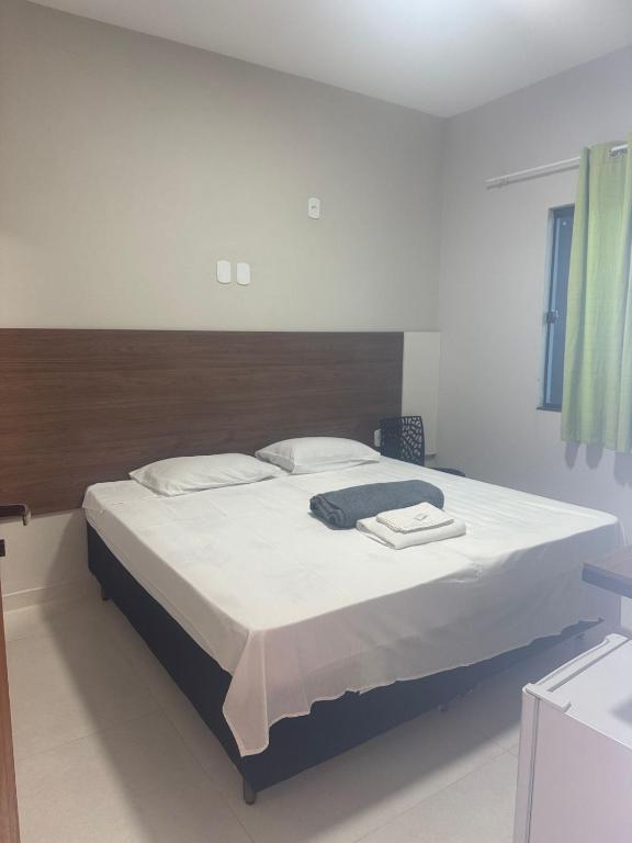 a bedroom with a large bed with white sheets at Pousada Avenida Farol in Campos dos Goytacazes