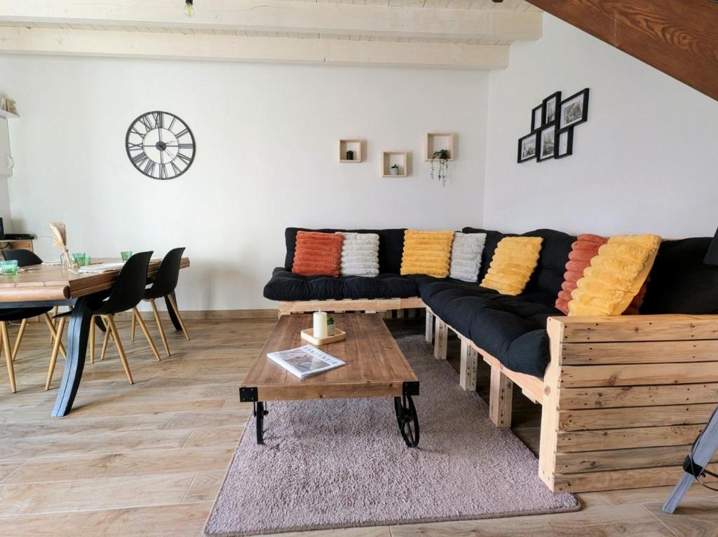 a living room with a black couch with colorful pillows at Le Nid Douillet - Duplex Bois & Charme in Mauléon