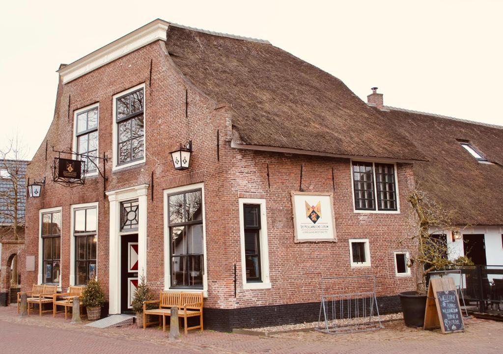 an old brick building with tables and chairs outside at Herberg De Hollandsche Leeuw in Nieuwkoop