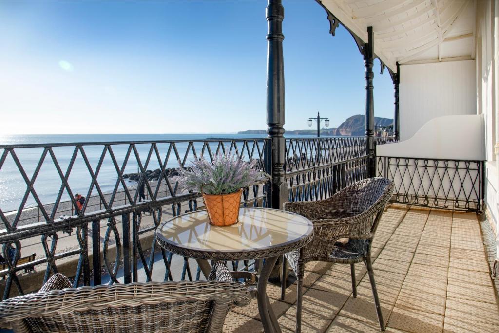 a table and chairs on a balcony with a view of the beach at Wyndham Balcony Apartment in Sidmouth