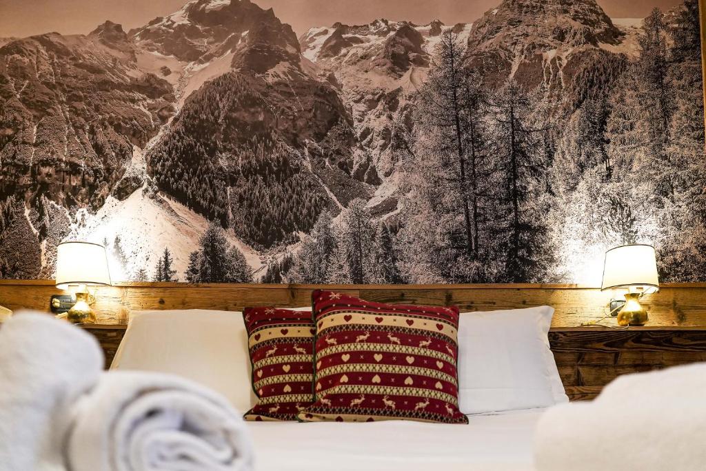 a bed with two pillows in front of a mountain mural at Hotel Jumeaux in Breuil-Cervinia
