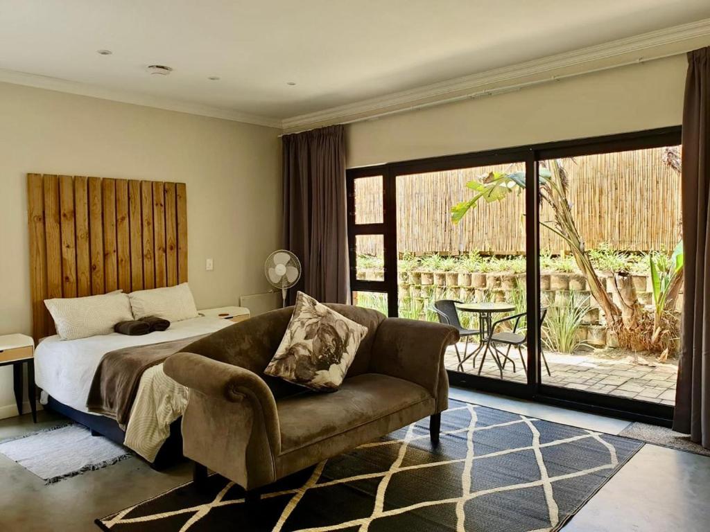 a bedroom with a bed and a couch and a patio at Fern Rivers Self-Catering Accommodation in Pietermaritzburg