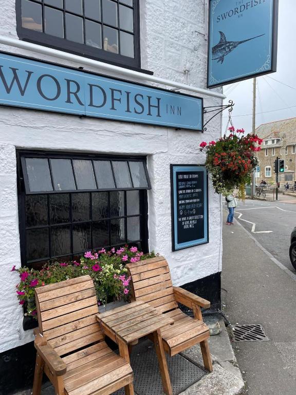 two wooden benches sitting outside of a seafood restaurant at The Swordfish Inn in Penzance