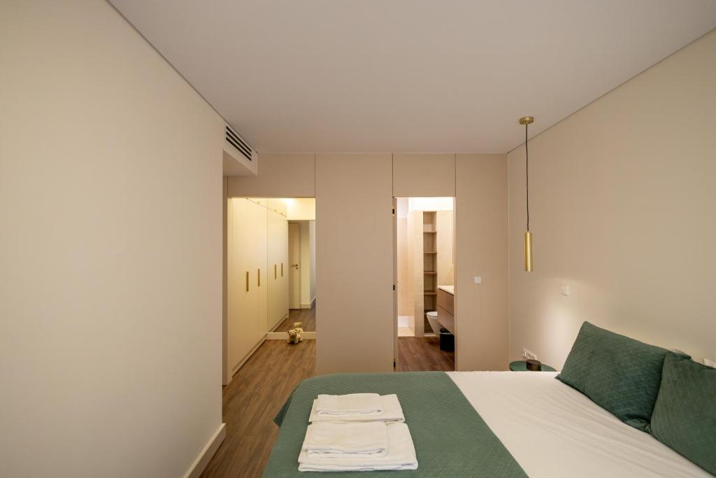 a bedroom with a white bed and a green couch at Music Apartment II in Bicas