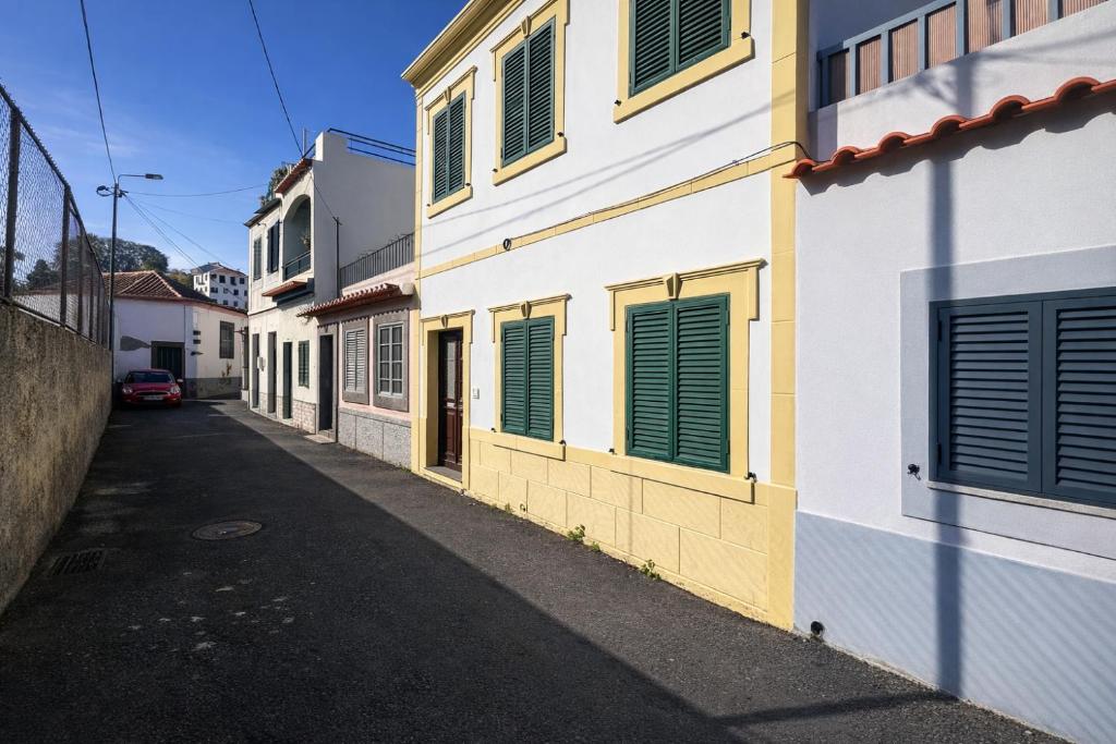 an alley with green shutters on a building at Violeta House in Funchal