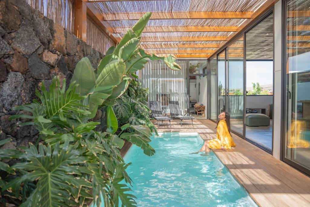 a pool in a house with a woman sitting in it at BaliHouse by Aura Collection in La Oliva