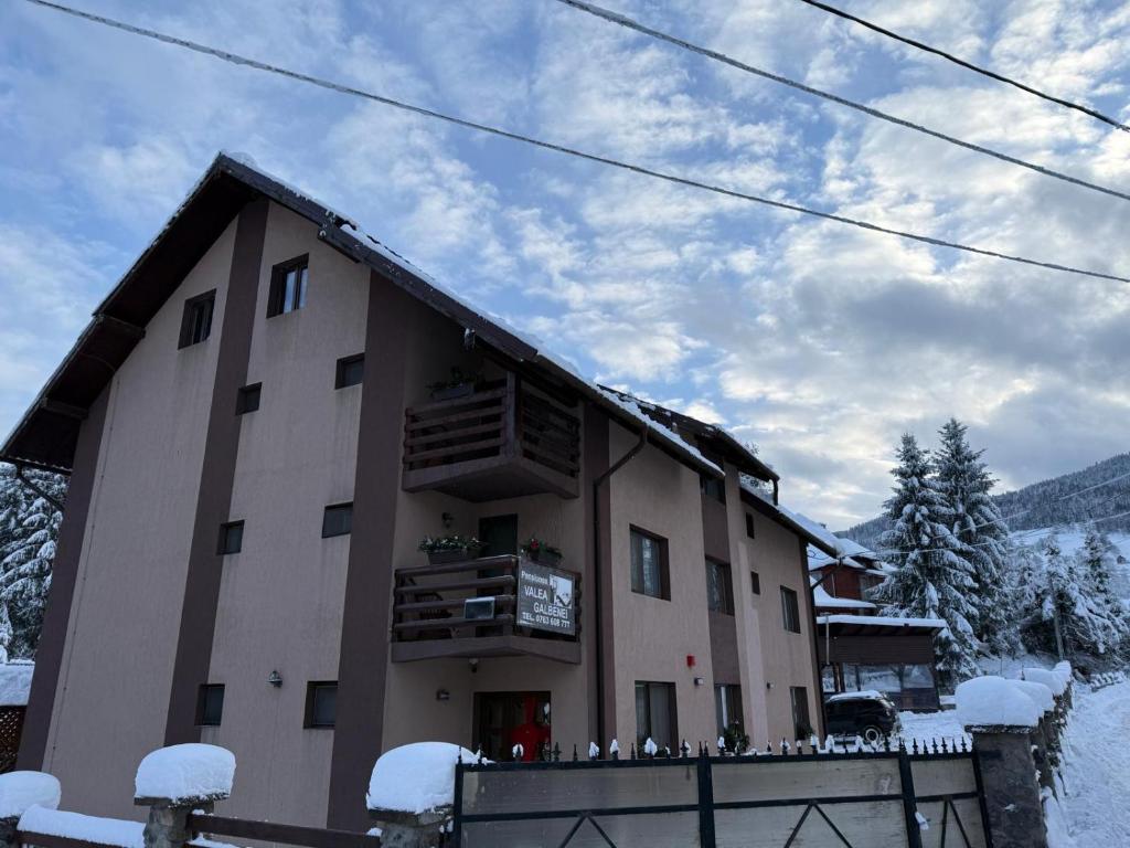 a building in the snow with snow on the ground at Pensiunea Valea Galbenei in Arieşeni