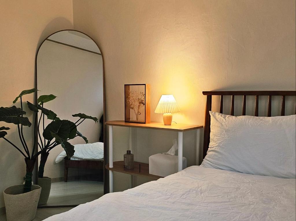 a bedroom with a bed with a mirror and a plant at Stay Onyu in Seoul