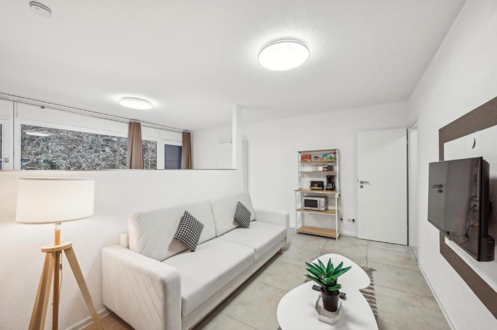 a living room with a white couch and a tv at Ramoni Apartments - Bergzauber Kniebis in Freudenstadt