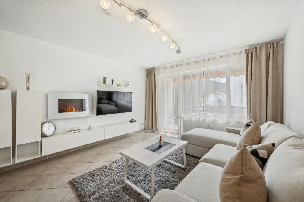 a white living room with a couch and a table at Ramoni Apartments - Naturglück in Enzklösterle