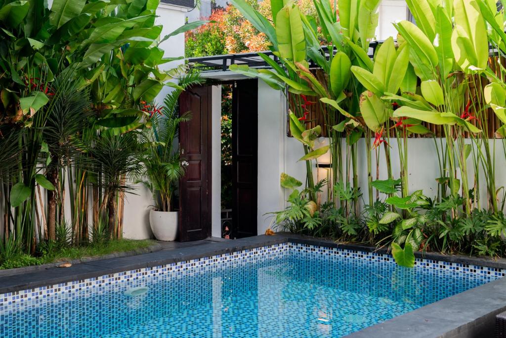 a swimming pool in front of a house with plants at The Aura Inn in Kerobokan