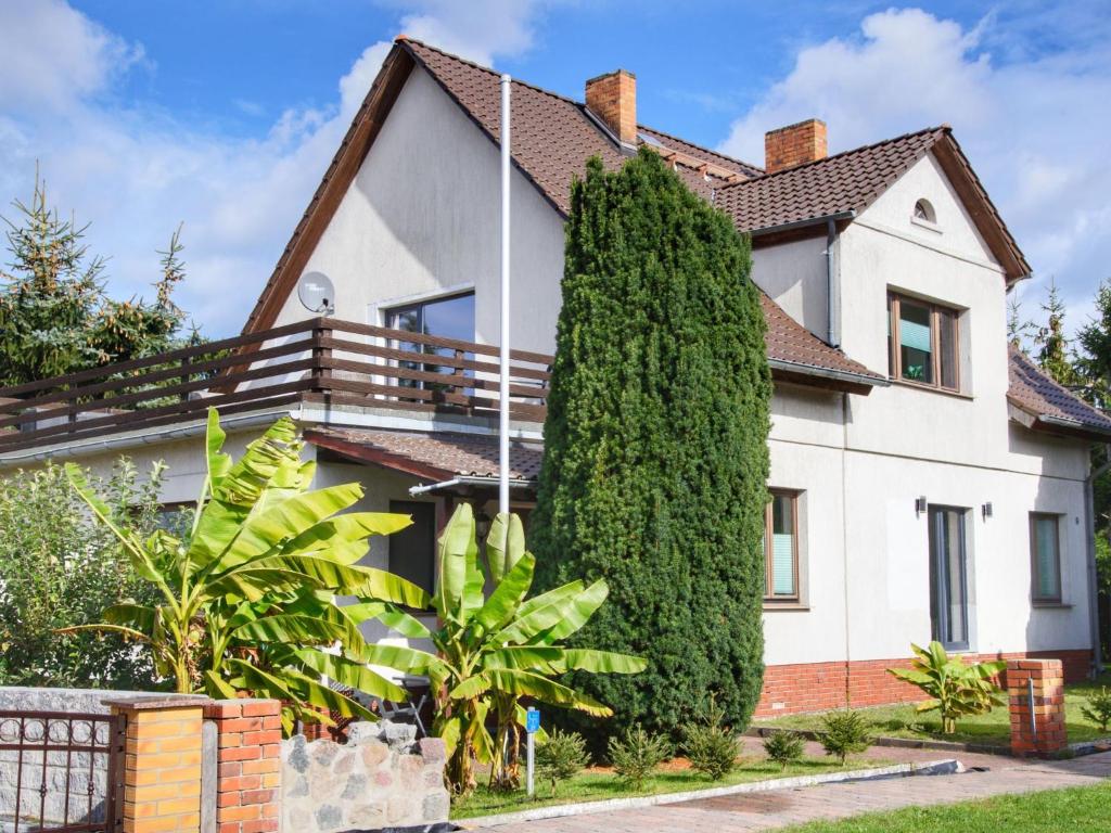 a white house with a large tree in front of it at Apartment mit Terrasse by Interhome in Mönkebude