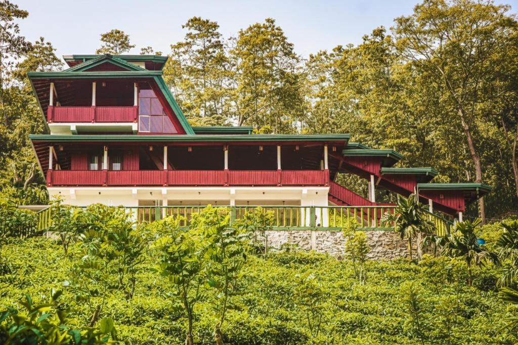 a red and white building with a green roof at Udadola Ecolodge in Deniyaya
