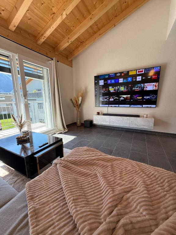 a bedroom with a large flat screen tv on the wall at Appartement Vue Montagne Vignoble Cosy Valais in Chamoson