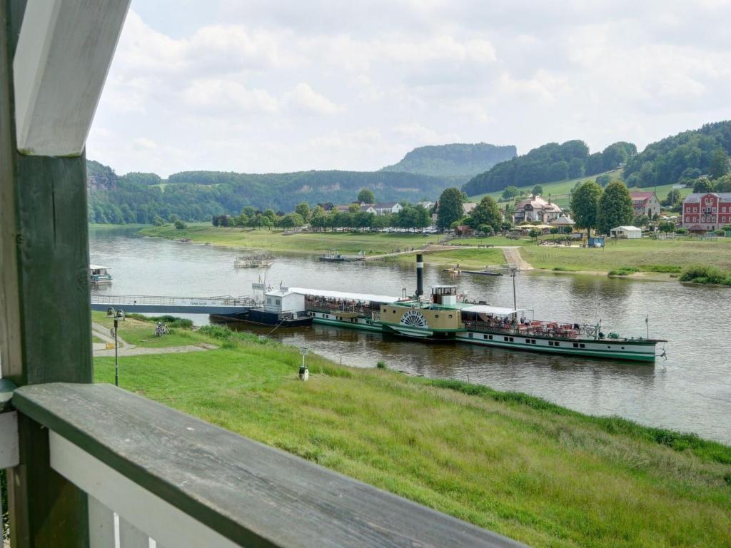 a boat traveling down a river next to a house at Apartment Bastei by Interhome in Kurort Rathen