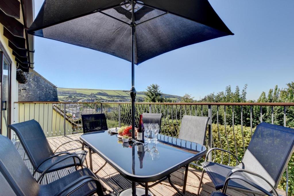 a table and chairs with an umbrella on a deck at 4 Bed in Croyde oc-sundow in Croyde