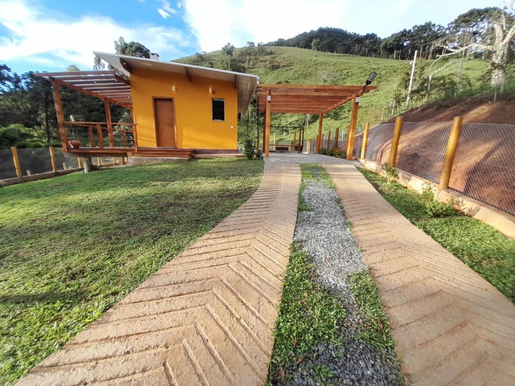 a house in the middle of a field with a walkway at Chalé Topázio Gonçalves in Gonçalves