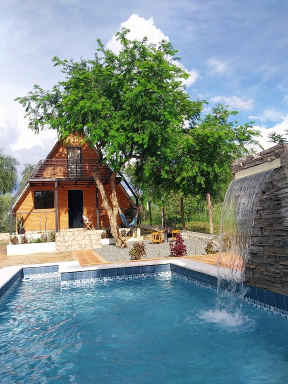a pool with a waterfall next to a house at Cabaña Alpina - Ecos del Cerro in Paraguarí