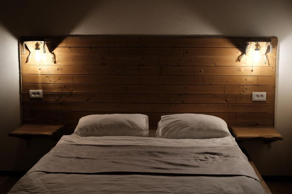 a bed with two pillows in a bedroom with two lights at Mansarda Kazbegi in Kazbegi