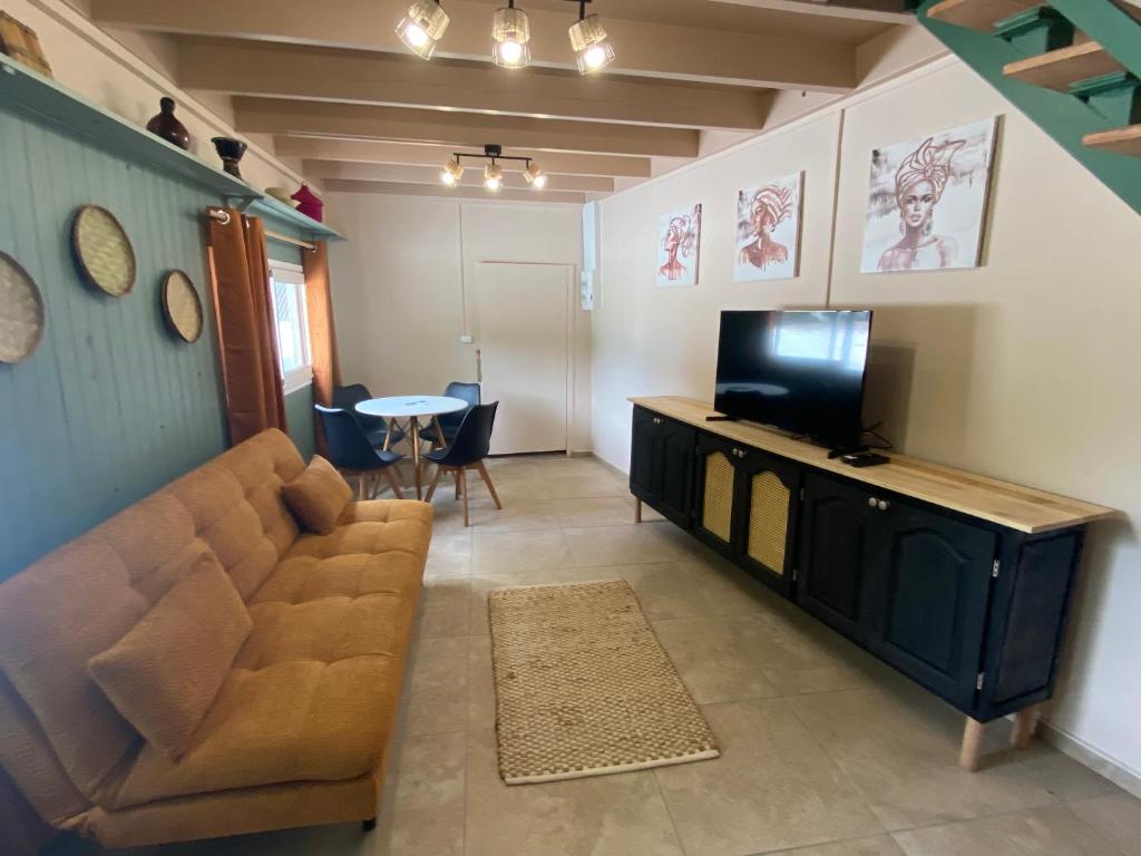 a living room with a couch and a television at Maison dans le quartier de terre sainte Nicolas in Saint-Pierre