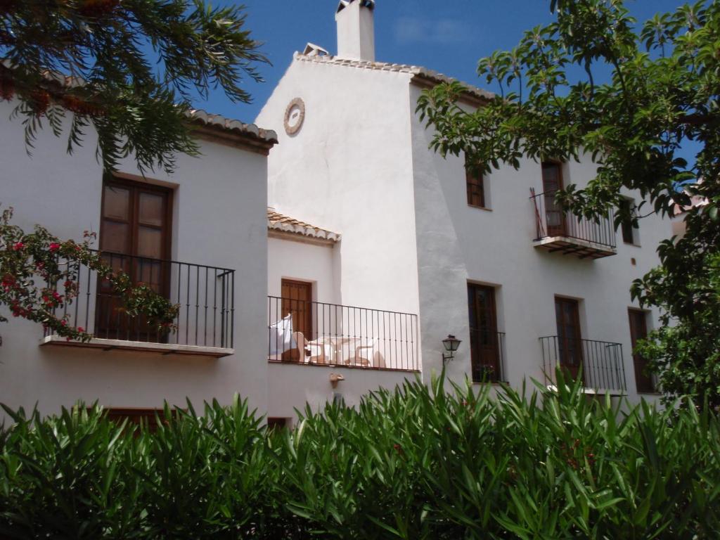 a white building with balconies and a clock tower at Casa de la Fuente in Tolox