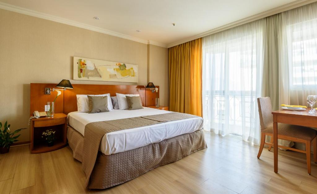 a hotel room with a large bed and a desk at Pineapples BPremium - Excelentes suítes in Rio de Janeiro