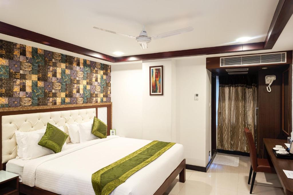 a bedroom with a large bed and a desk at Treebo Trend Empire in Vijayawāda