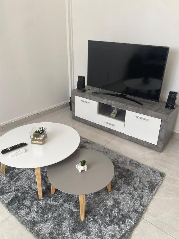 a living room with two tables and a flat screen tv at Le Temps d une Escale in Trois-Rivières