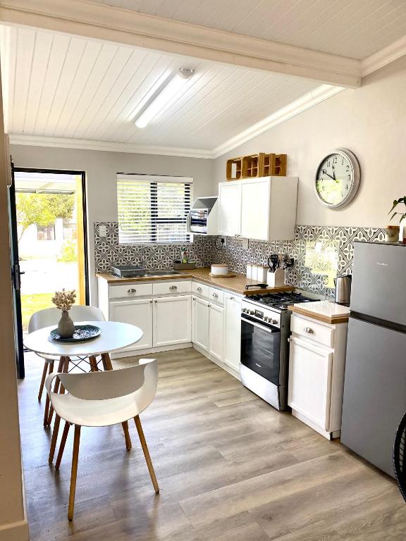 a kitchen with white appliances and a table and a table and chairs at Living Lite 1 and 2 in Kleinmond