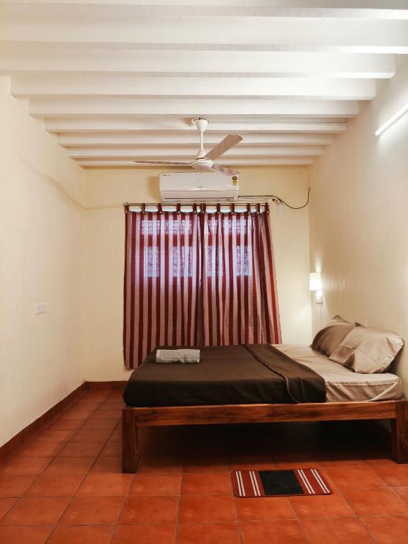 a bedroom with a bed with a red curtain at La Maison D'Ellappa in Pondicherry
