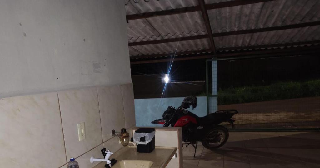 a motorcycle parked in a garage with a light at Casa temporada soares in São José da Barra