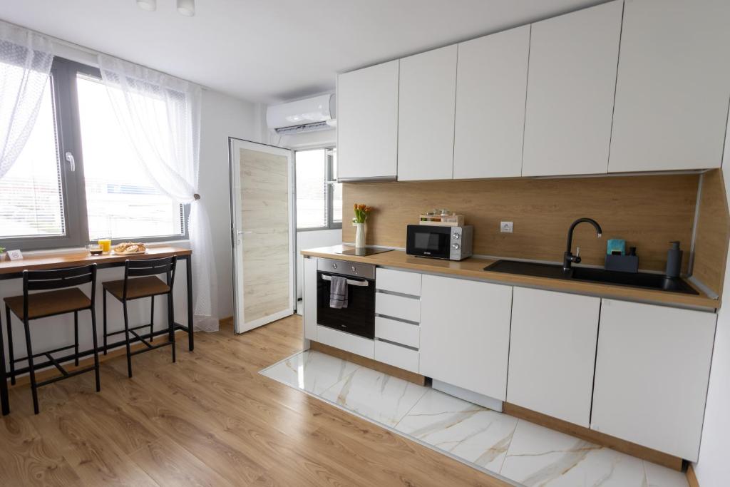 a kitchen with white cabinets and a table at Hotel Cheese in Shumen