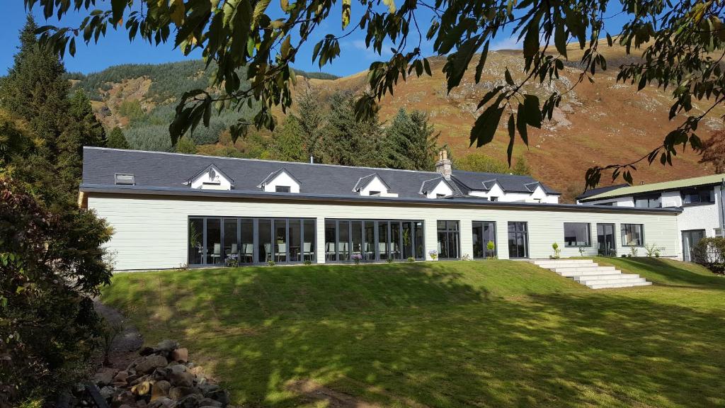 a large white house with mountains in the background at The Brander Lodge Hotel and Bistro in Taynuilt
