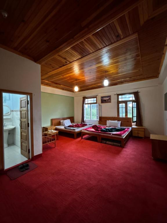 a large room with two beds and a red rug at Kehkashan in Shongran