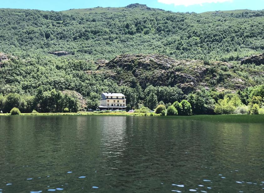 a house sitting on the shore of a lake at Hotel Don Pepe Lago de Sanabria in Ribadelago