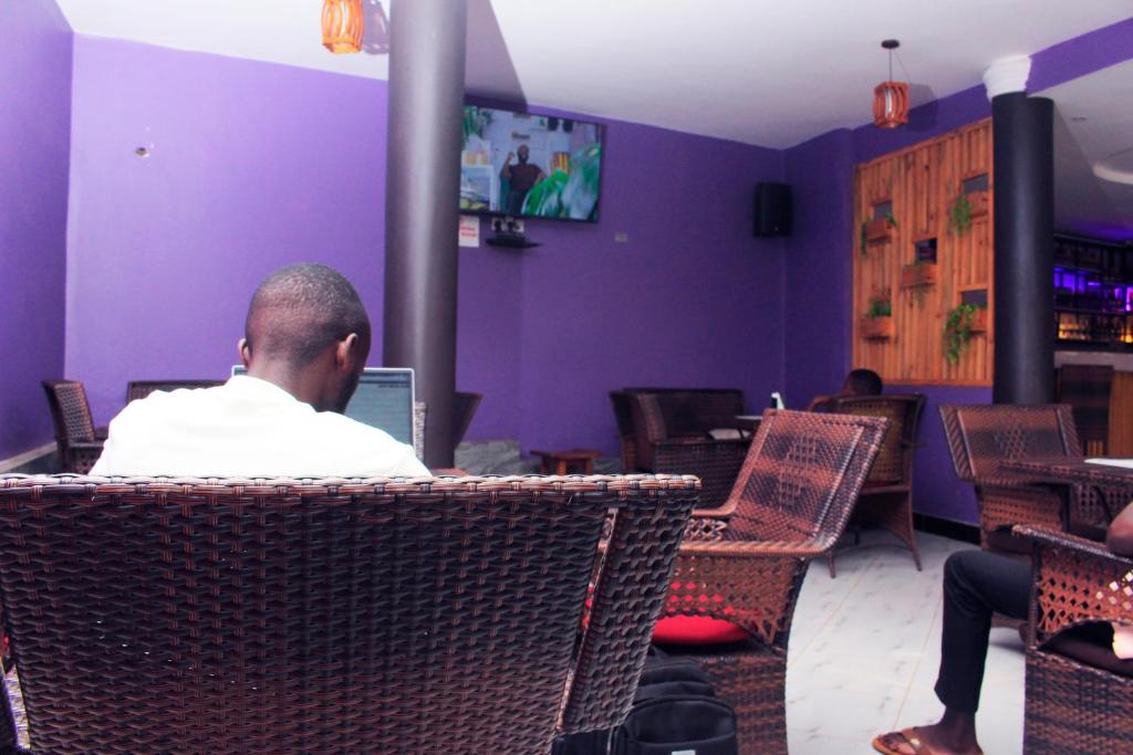 a man sitting in a chair using a laptop at Moto-Moto Cottages in Mbarara