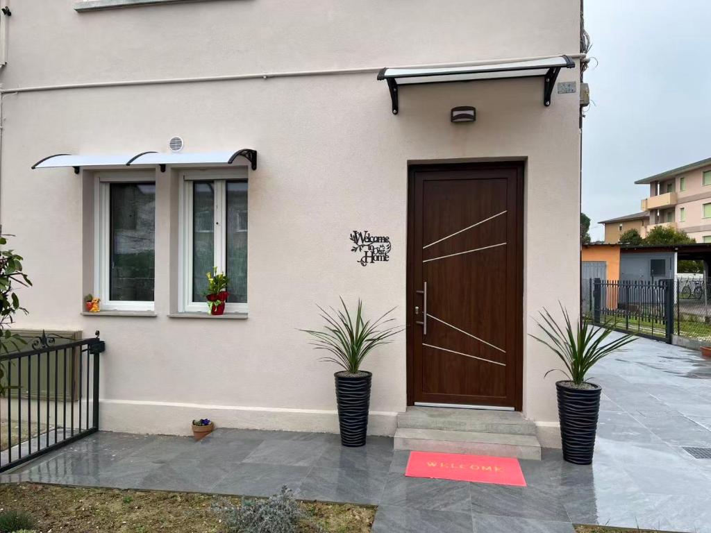 a house with a brown door and two plants at James Home in Quarto dʼAltino